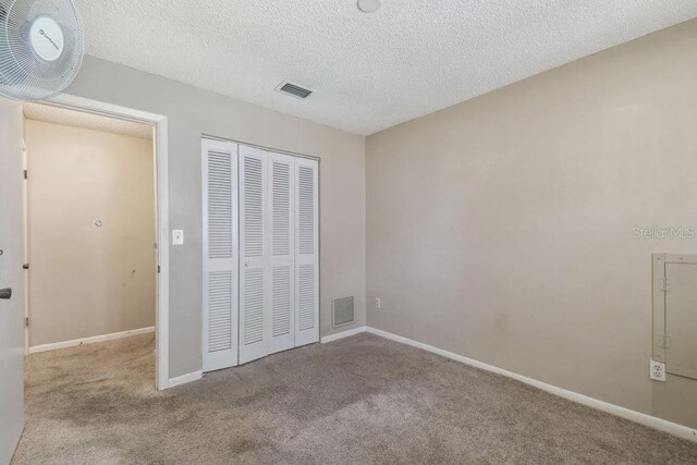 8030 San Bernardino Dr, Port Richey, FL 34668 - unfurnished bedroom featuring carpet floors, a closet, and a textured ceiling