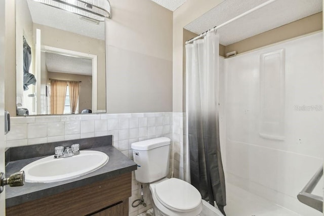 8030 San Bernardino Dr, Port Richey, FL 34668 - bathroom featuring a shower stall, vanity, a textured ceiling, tile walls, and a wainscoted wall