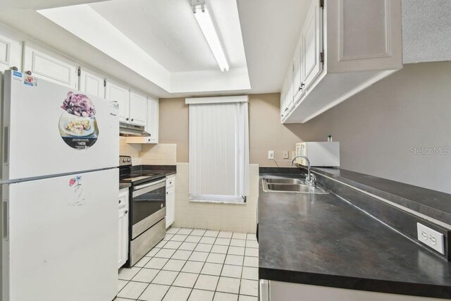 8030 San Bernardino Dr, Port Richey, FL 34668 - kitchen featuring freestanding refrigerator, electric stove, under cabinet range hood, white cabinetry, and light tile patterned floors