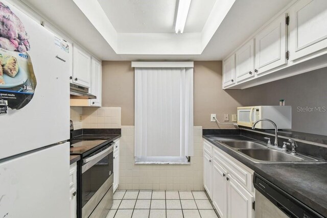 8030 San Bernardino Dr, Port Richey, FL 34668 - kitchen featuring stainless steel appliances, under cabinet range hood, a raised ceiling, light tile patterned floors, and white cabinets
