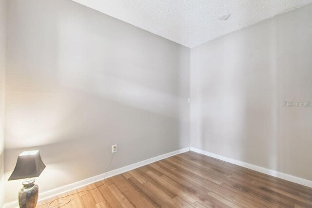 8030 San Bernardino Dr, Port Richey, FL 34668 - empty room with wood finished floors and a textured ceiling