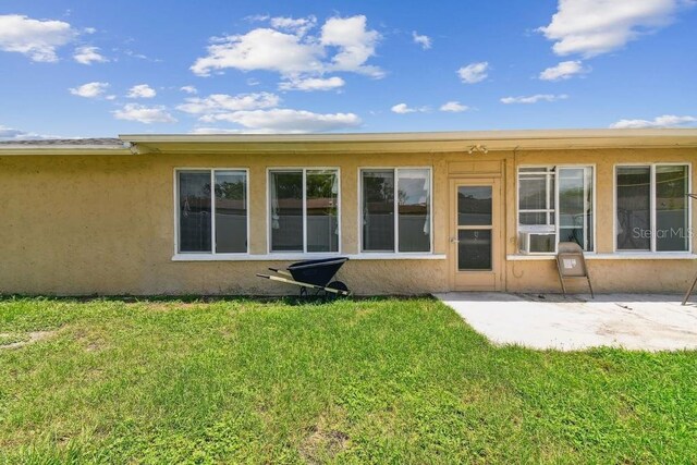 8030 San Bernardino Dr, Port Richey, FL 34668 - back of house with a lawn, stucco siding, a patio area, and cooling unit