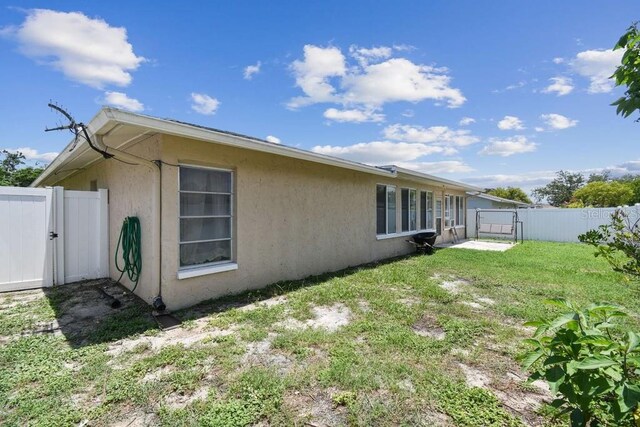 8030 San Bernardino Dr, Port Richey, FL 34668 - view of side of property featuring a gate, a fenced backyard, and stucco siding