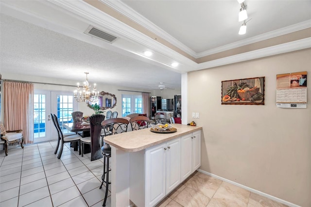 2182 Corinne Ct S Unit C, Saint Petersburg, FL 33712 - kitchen featuring light countertops, a peninsula, a breakfast bar area, white cabinetry, and ornamental molding