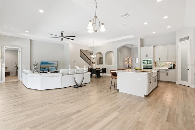 5426 Wayfarer Ave, Apollo Beach, FL 33572 - kitchen with arched walkways, open floor plan, light countertops, a center island with sink, and recessed lighting