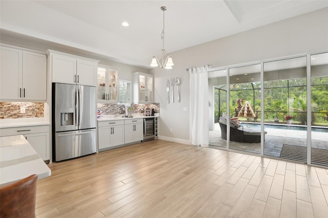 5426 Wayfarer Ave, Apollo Beach, FL 33572 - kitchen featuring stainless steel fridge, wine cooler, decorative backsplash, light countertops, and a chandelier