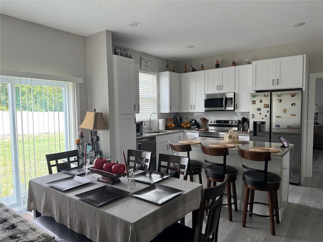 4043 SW 156th Pl, Ocala, FL 34473 - kitchen with appliances with stainless steel finishes, light wood-style flooring, white cabinets, a textured ceiling, and decorative backsplash