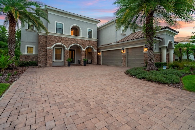 1507 Amarone Pl, Lutz, FL 33548 - mediterranean / spanish home featuring stucco siding, decorative driveway, an attached garage, and stone siding