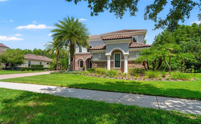 1507 Amarone Pl, Lutz, FL 33548 - mediterranean / spanish house featuring stone siding, stucco siding, a tiled roof, and a front yard
