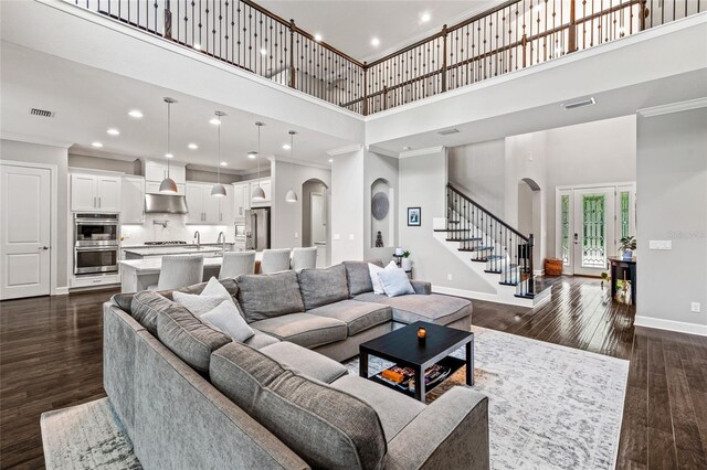 1507 Amarone Pl, Lutz, FL 33548 - living room featuring arched walkways, a towering ceiling, ornamental molding, stairs, and dark wood-type flooring