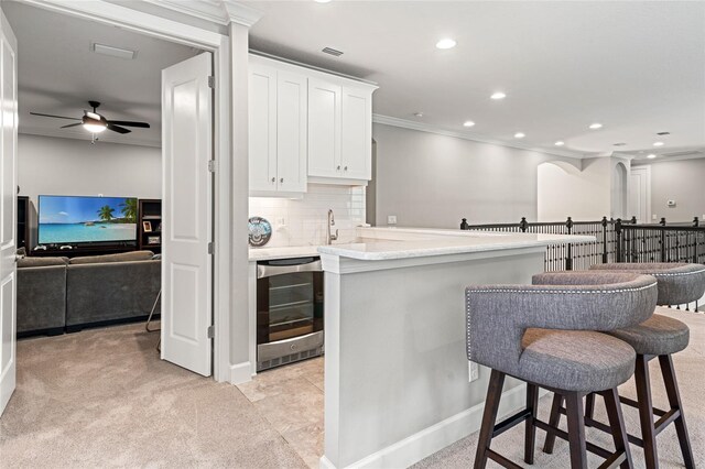 1507 Amarone Pl, Lutz, FL 33548 - kitchen with beverage cooler, a ceiling fan, light countertops, white cabinets, and crown molding