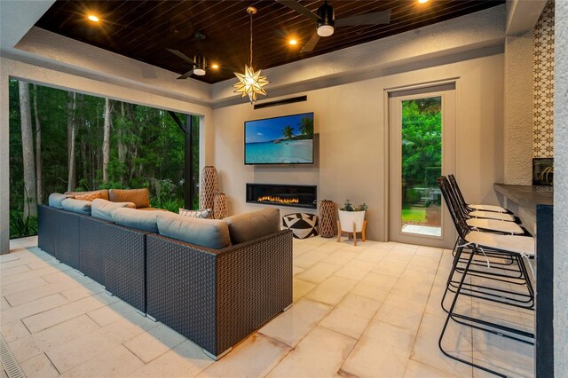 1507 Amarone Pl, Lutz, FL 33548 - living room with a warm lit fireplace, a tray ceiling, wooden ceiling, and ceiling fan
