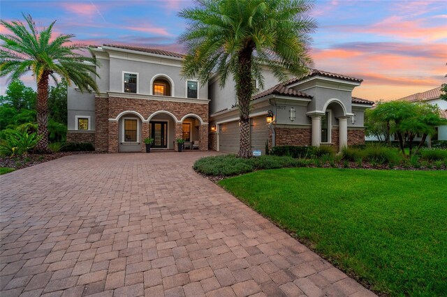 1507 Amarone Pl, Lutz, FL 33548 - mediterranean / spanish house with stucco siding, decorative driveway, a yard, stone siding, and a garage