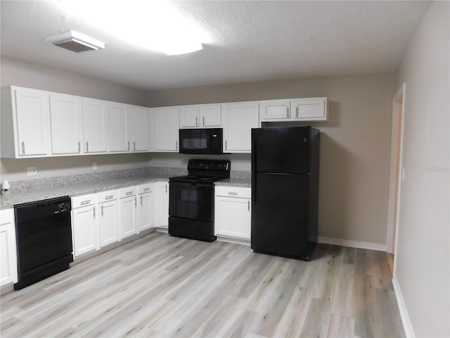 507 Francis Blvd, Lakeland, FL 33801 - kitchen with black appliances, white cabinets, light wood finished floors, light stone countertops, and a textured ceiling