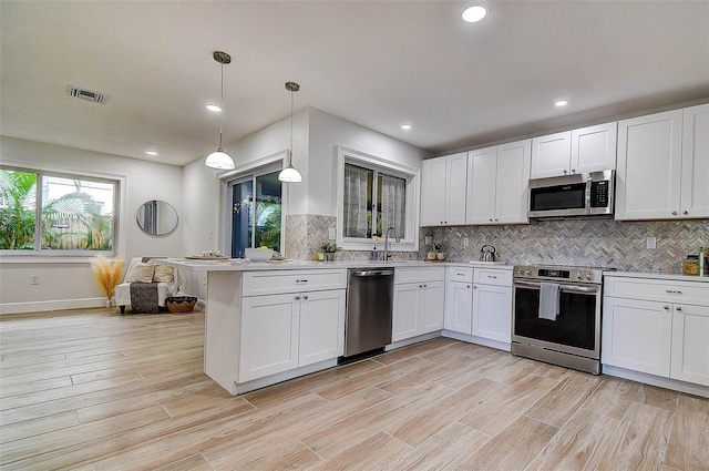 10900 65th Way N, Pinellas Park, FL 33782 - kitchen with stainless steel appliances, backsplash, white cabinets, light countertops, and recessed lighting