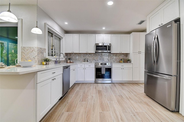 10900 65th Way N, Pinellas Park, FL 33782 - kitchen featuring appliances with stainless steel finishes, white cabinetry, light countertops, hanging light fixtures, and decorative backsplash