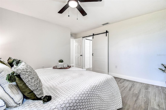 10900 65th Way N, Pinellas Park, FL 33782 - bedroom featuring wood finished floors, a barn door, and a ceiling fan