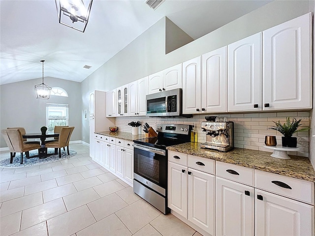 1437 Stonehenge Way, Palm Harbor, FL 34683 - kitchen featuring appliances with stainless steel finishes, decorative backsplash, lofted ceiling, dark stone counters, and white cabinets