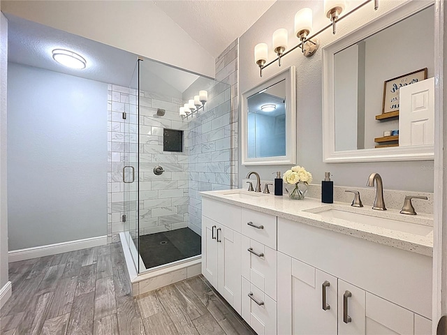 1437 Stonehenge Way, Palm Harbor, FL 34683 - full bathroom featuring lofted ceiling, a stall shower, double vanity, wood finished floors, and a textured ceiling