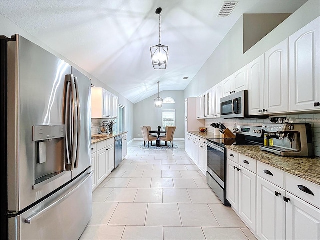1437 Stonehenge Way, Palm Harbor, FL 34683 - kitchen featuring stainless steel appliances, backsplash, lofted ceiling, dark stone countertops, and white cabinetry