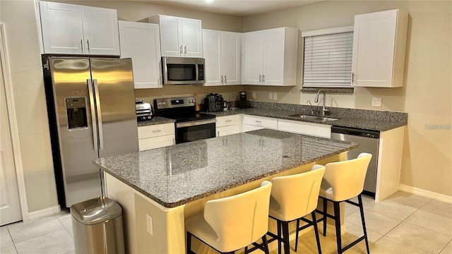 31363 Sun Kettle Loop, Wesley Chapel, FL 33545 - kitchen featuring stainless steel appliances, light tile patterned floors, white cabinets, dark stone counters, and a breakfast bar