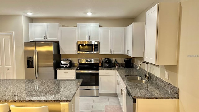 31363 Sun Kettle Loop, Wesley Chapel, FL 33545 - kitchen with appliances with stainless steel finishes, white cabinetry, dark stone counters, light tile patterned flooring, and recessed lighting