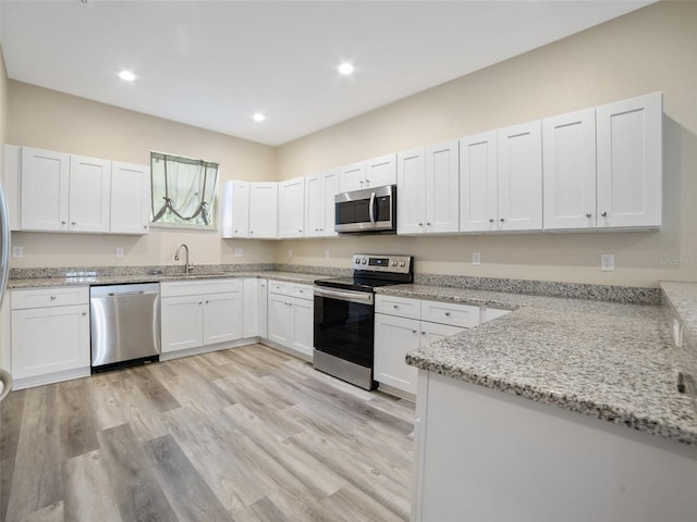 239 Burbank Ave, Lakeland, FL 33801 - kitchen with stainless steel appliances, white cabinetry, light stone counters, and recessed lighting