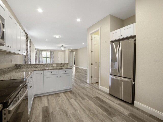 239 Burbank Ave, Lakeland, FL 33801 - kitchen featuring stainless steel appliances, a peninsula, white cabinetry, arched walkways, and light wood-type flooring