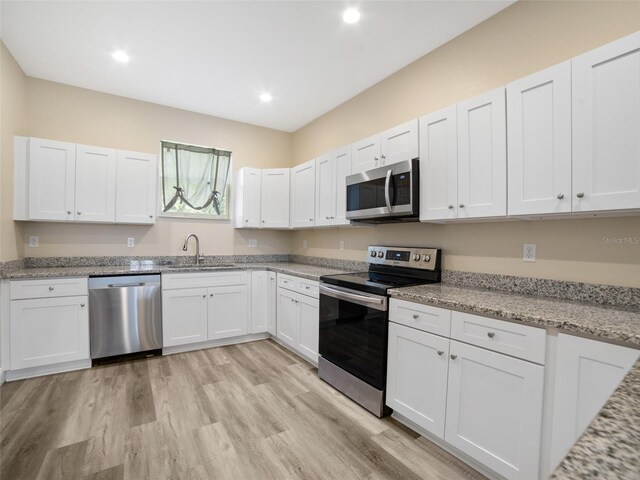 239 Burbank Ave, Lakeland, FL 33801 - kitchen featuring appliances with stainless steel finishes, white cabinets, light wood-type flooring, light stone countertops, and recessed lighting