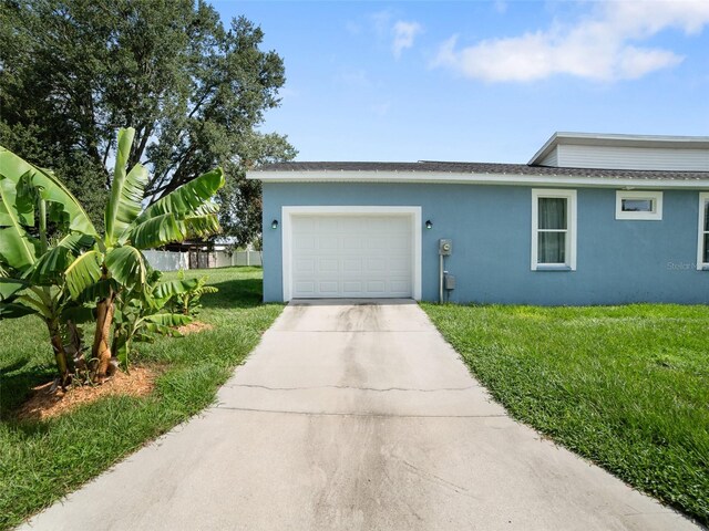 239 Burbank Ave, Lakeland, FL 33801 - view of front facade featuring stucco siding, driveway, an attached garage, and a front lawn