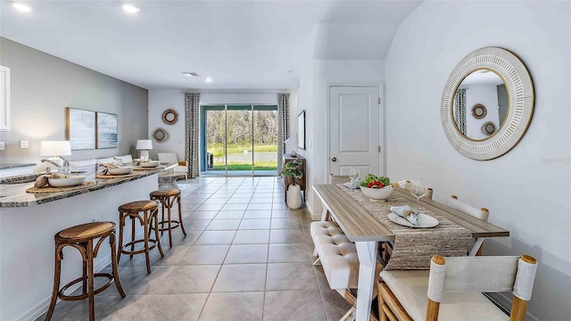 8098 Swan Mist Way, Wesley Chapel, FL 33545 - kitchen featuring a breakfast bar area, light tile patterned floors, recessed lighting, stone counters, and open floor plan