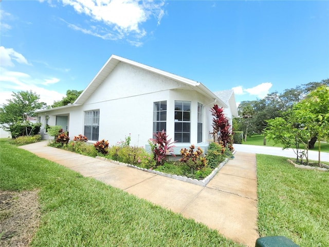 11653 Orleans Ln, Port Richey, FL 34668 - view of side of property with a lawn and stucco siding