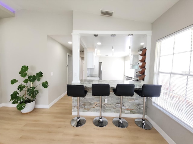 11653 Orleans Ln, Port Richey, FL 34668 - kitchen featuring vaulted ceiling, white cabinets, healthy amount of natural light, a peninsula, and light wood finished floors