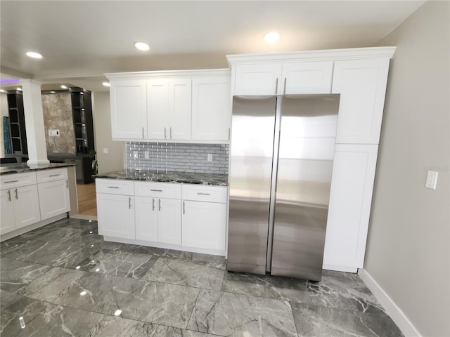 11653 Orleans Ln, Port Richey, FL 34668 - kitchen with stainless steel fridge, decorative backsplash, white cabinetry, dark stone countertops, and recessed lighting