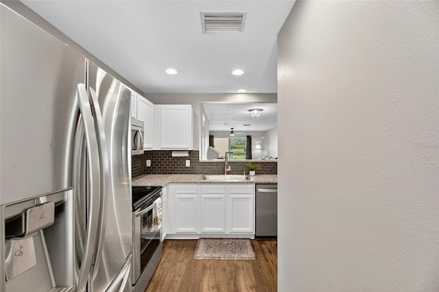 6919 Hawthorne Trace Ln, Riverview, FL 33578 - kitchen featuring stainless steel appliances, tasteful backsplash, white cabinetry, dark wood-type flooring, and light stone counters