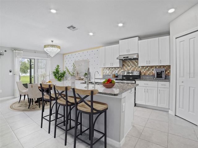 13646 Wild Ginger St, Riverview, FL 33579 - kitchen featuring under cabinet range hood, electric stove, stone counters, a kitchen breakfast bar, and a chandelier