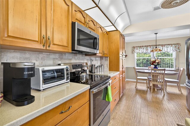 2201 Hartlebury Way Unit 2201, Sun City Center, FL 33573 - kitchen with stainless steel appliances, light wood finished floors, brown cabinets, backsplash, and hanging light fixtures