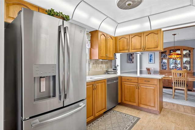 2201 Hartlebury Way Unit 2201, Sun City Center, FL 33573 - kitchen with stainless steel appliances, light wood-style floors, light countertops, a peninsula, and brown cabinets