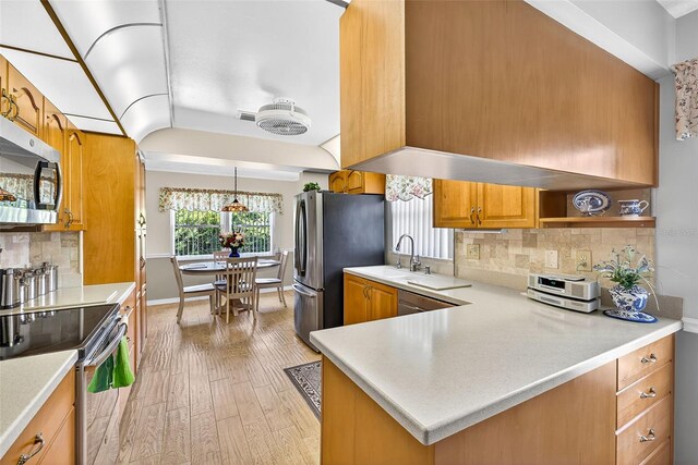 2201 Hartlebury Way Unit 2201, Sun City Center, FL 33573 - kitchen featuring stainless steel appliances, light wood-style flooring, brown cabinetry, light countertops, and backsplash