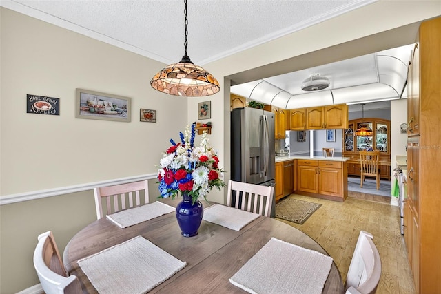2201 Hartlebury Way Unit 2201, Sun City Center, FL 33573 - dining area with light wood finished floors, a textured ceiling, and ornamental molding