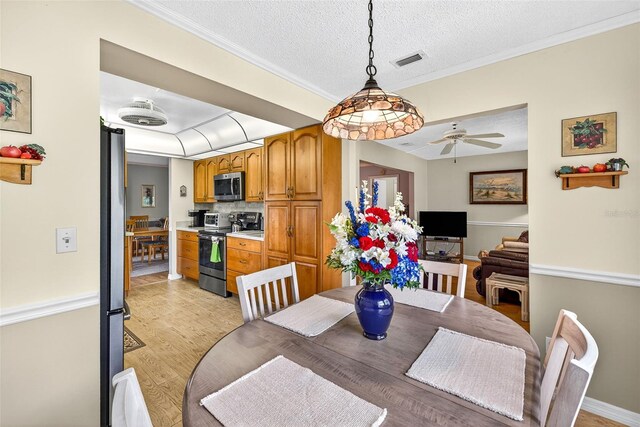 2201 Hartlebury Way Unit 2201, Sun City Center, FL 33573 - dining space featuring light wood-style flooring, ceiling fan, ornamental molding, and a textured ceiling
