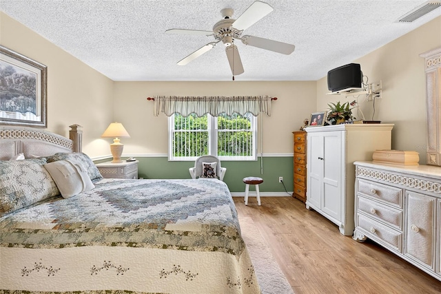2201 Hartlebury Way Unit 2201, Sun City Center, FL 33573 - bedroom featuring light wood-style flooring, a textured ceiling, and a ceiling fan