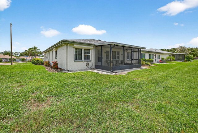2201 Hartlebury Way Unit 2201, Sun City Center, FL 33573 - back of property with a sunroom, a lawn, and stucco siding