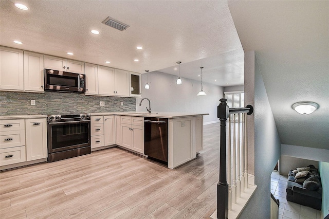 14865 Seminole Trl, Seminole, FL 33776 - kitchen with appliances with stainless steel finishes, a peninsula, light wood-style flooring, decorative backsplash, and light countertops
