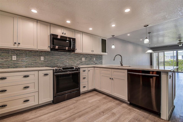 14865 Seminole Trl, Seminole, FL 33776 - kitchen with stainless steel microwave, electric range oven, dishwashing machine, a peninsula, and a textured ceiling