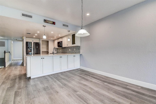 14865 Seminole Trl, Seminole, FL 33776 - kitchen with black fridge, a peninsula, light wood-style flooring, tasteful backsplash, and recessed lighting