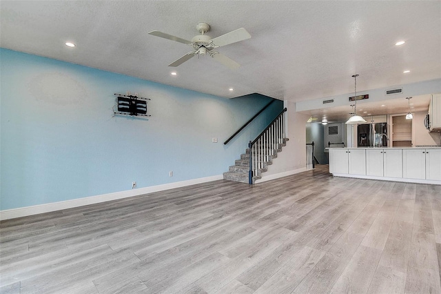 14865 Seminole Trl, Seminole, FL 33776 - unfurnished living room featuring light wood-type flooring, ceiling fan, recessed lighting, stairway, and a textured ceiling