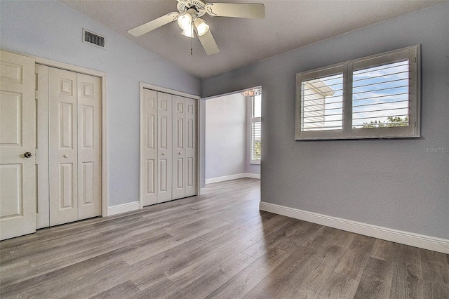 14865 Seminole Trl, Seminole, FL 33776 - unfurnished bedroom with lofted ceiling, two closets, wood finished floors, and a ceiling fan