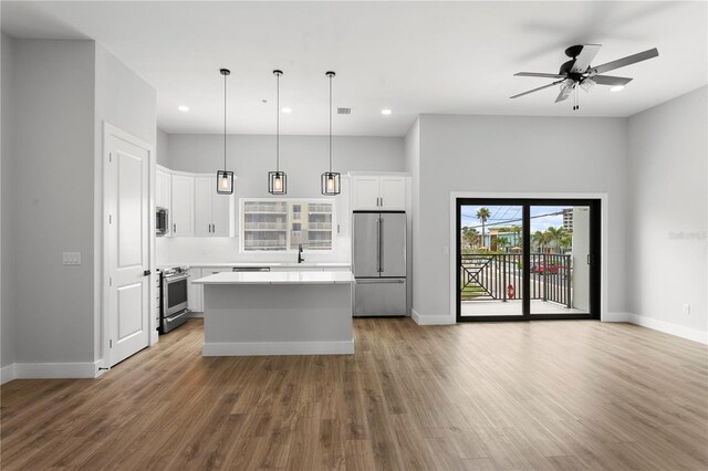 11605 1st St E Unit 2, Treasure Island, FL 33706 - kitchen featuring appliances with stainless steel finishes, a center island, recessed lighting, wood finished floors, and light countertops