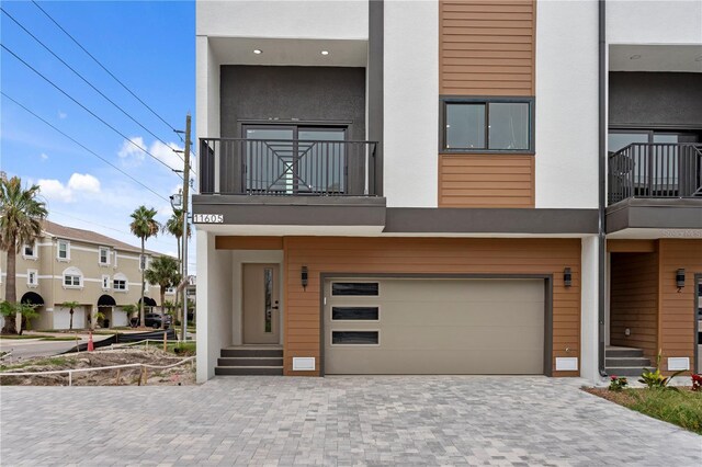 11605 1st St E Unit 2, Treasure Island, FL 33706 - view of front of property featuring a balcony, an attached garage, stucco siding, and decorative driveway